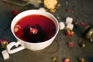 Cup of rose tea with sugar on wooden table