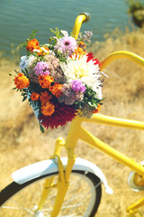 Obrazy na Szkle  Piękny żółty rower z bukietem kwiatów w koszu, na zewnątrz