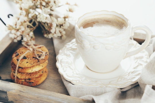 Cup of coffee and pile of tasty cookies with chocolate crumbs on wooden tray