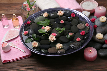 Spa composition of flowers and stones in water on wooden background