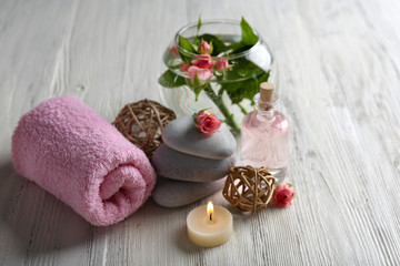 Fototapeta na wymiar Composition of flowers, candles and stones on white wooden background, in spa salon