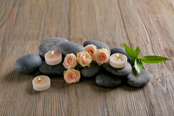 Spa composition of candles, flowers and stones on brown wooden background