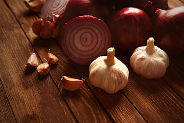 Fresh red onions with garlic on wooden background