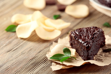 Piece of chocolate cake decorated with flowers on brown wooden table