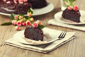 Piece of chocolate cake decorated with flowers on brown wooden table