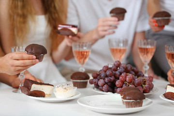 Friends hands with glasses of wine and desserts, close up