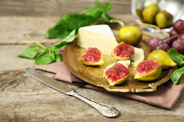 Ripe figs and cheese on tray, on wooden background