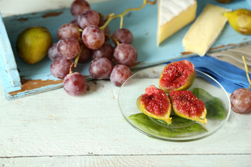 Ripe figs on plate, on color wooden background