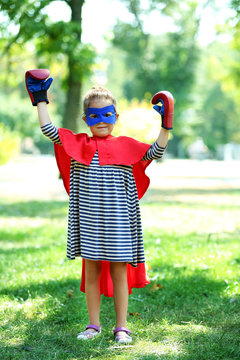 Little girl dressed as superhero in boxing gloves at the park