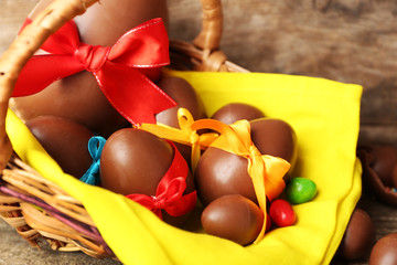 Chocolate Easter eggs in basket on wooden background