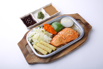 Salmon steak on hot plate with three sauce isolated on white