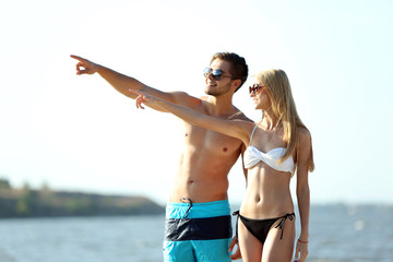 Happy couple pointing at the beach, outdoors