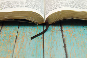 Opened Bible with a bookmark on Wood - obrazy, fototapety, plakaty