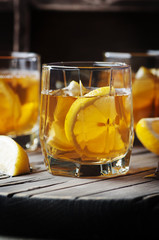 Cold whiskey with ice and lemon on the vintage table