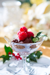 Elegant chocolate truffle mousse with raspberries in a vintage German crystal dish with festive holiday table setting