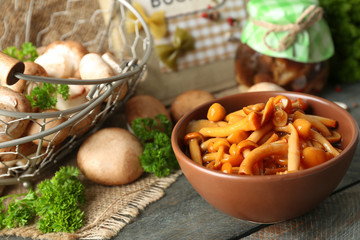 Delicious marinated mushrooms in bowl on wooden background