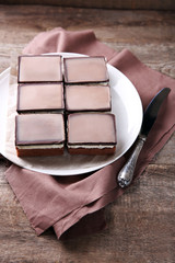 Delicious chocolate brownies on plate, on wooden background