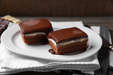 Delicious chocolate brownies on plate, on wooden background