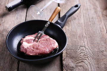 Marbled beef steak and wine bottle on wooden background