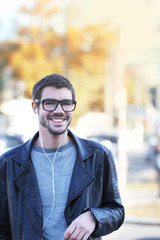 Young man listening to music and walking along the street