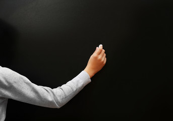 View on schoolboy's hand writing at the blackboard