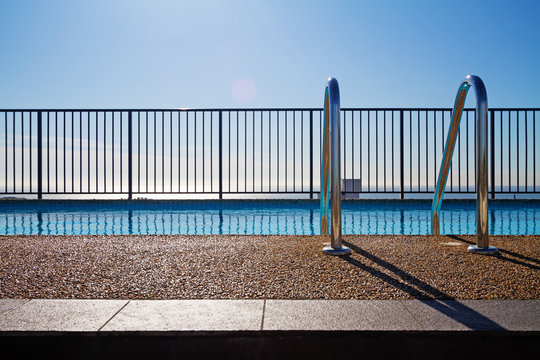 Swimming pool edge with ladder and sky background
