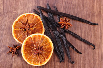 Fragrant vanilla, star anise and dried orange on wooden surface plank