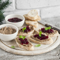 Sandwiches with chicken liver pate and cranberry sauce, served on a light wooden board