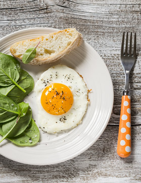 fried egg and fresh spinach - a healthy Breakfast or snack, on a wooden surface
