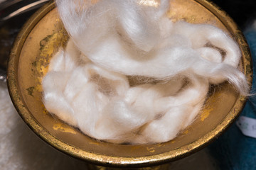 Processed white wool in old iron vase
