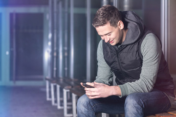 Junger Mann lächelnd vertieft ins Smartphone
