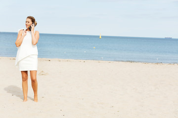 Young elegant beautiful woman talking on the phone on the beach