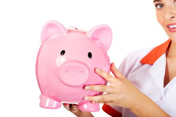 Young beautiful female doctor or nurse holding a piggybank