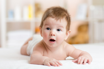 Funny small baby lying on the belly and smiling