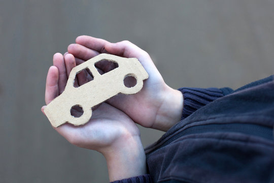 young homeless boy holds a cardboard car