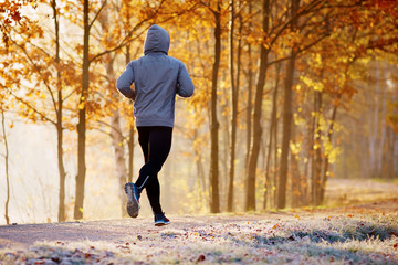 Young man running in the park during autumn morning