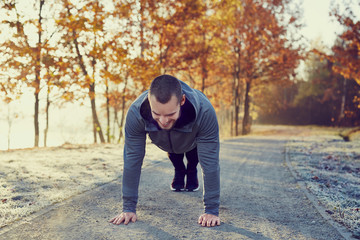 Young happuy man doing pushups exercise at morning during autumn