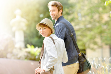 Happy young woman walking in park, holding boyfriend's hand