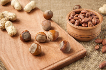  peanut,  hazelnuts in wooden bowls on wooden and burlap, sack burlap