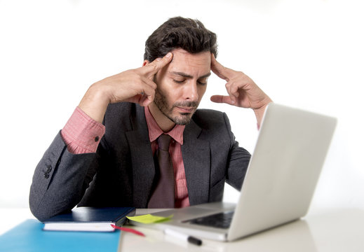 young attractive businessman sitting at office desk working on computer laptop suffering headache