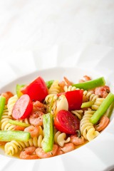 Pasta with vegetables and prawns on the white background vertical