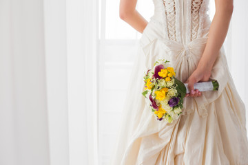 Bride holding her wedding flowers behind her back