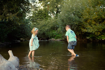 Young siblings playing in river, exploration concept