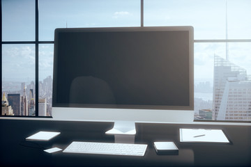 Fototapeta premium Blank computer monitor with office accessories on a table in the