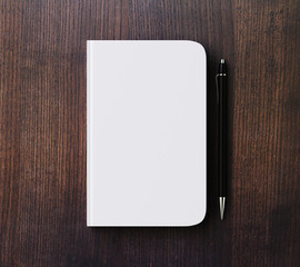 Blank white diary cover and pen on brown wooden table, mock up