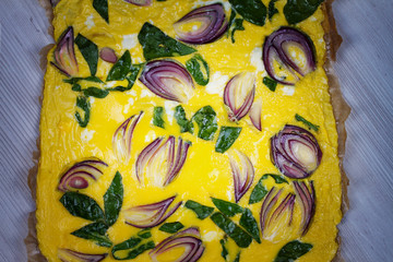 Omelette with blue onion and spinach on parchment. View from above, top studio shot