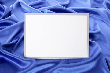 Blank greetings card or invitation with blue satin background.