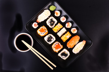 Sushi set served on a plate, soy cheese, lime on black background