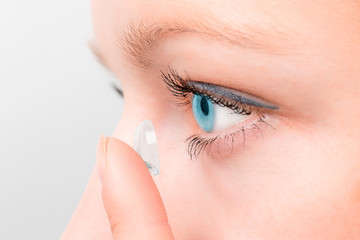 Naklejka premium Woman inserting a contact lens in eye.