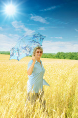 Senior woman with parasol under bright sun